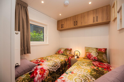Habitación acogedora con dos camas individuales y ropa de cama floral en Tiny Loft, Veluwepark de Bosgraaf.
