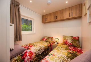 Habitación acogedora con dos camas individuales y ropa de cama floral en Tiny Loft, Veluwepark de Bosgraaf.