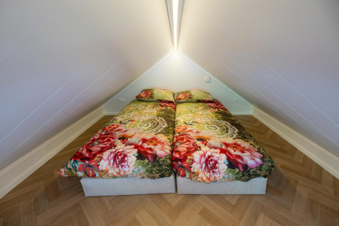 Dos camas individuales con ropa de cama floral en un acogedor altillo en Tiny Loft, Veluwepark de Bosgraaf.