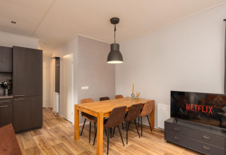 Área de comedor y sala acogedora con mesa y TV en Sand Lodge Comfort, Veluwepark de Bosgraaf, Países Bajos.