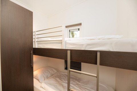 Habitación con literas y ropa de cama blanca en Sand Lodge Comfort de Veluwepark de Bosgraaf, Países Bajos.