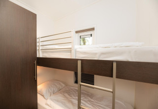 Værelse med køjesenge og hvidt sengetøj på Sand Lodge Comfort ved Veluwepark de Bosgraaf, Holland.