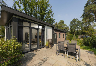 Terraza exterior y jardín en Heather Lodge, Veluwepark de Bosgraaf, Países Bajos, rodeado de naturaleza.