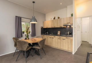 Cocina moderna y comedor en Heather Lodge en Veluwepark de Bosgraaf, Países Bajos, con detalles en madera.