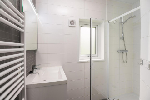 Baño moderno con ducha, lavabo, espejo y ventana en Heather Lodge, Veluwepark de Bosgraaf, Países Bajos.