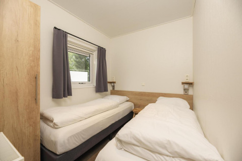 Dormitorio con dos camas individuales en Heather Lodge, Veluwepark de Bosgraaf, Países Bajos, decoración clara.