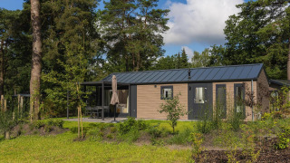 Velthorst Comfort lodge surrounded by greenery and trees, featuring a modern exterior and outdoor seating area.