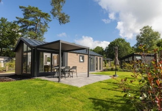 Buitenzicht van Velthorst Comfort-lodge in Veluwepark de Bosgraaf, Nederland, met terras en grasveld.