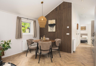 Comedor moderno con pared de madera en la cabaña Velthorst Comfort de Veluwepark de Bosgraaf, Países Bajos.