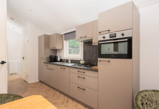 Moderne keuken in de Velthorst Comfort lodge op Veluwepark de Bosgraaf, Nederland, met oven en kasten.