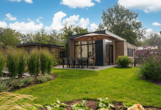 Moderne lodge Cannenburch met bubbelbad in Veluwepark de Bosgraaf, Nederland, midden in een groene tuin.