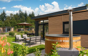 Buitenaanzicht van Lodge Cannenburch met hottub bij Veluwepark de Bosgraaf in Nederland, omgeven door natuur.