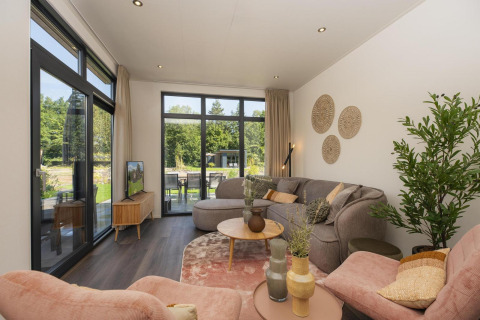 Soggiorno moderno in un lodge Cannenburch con grandi finestre al Veluwepark de Bosgraaf, Paesi Bassi.