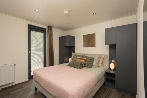 Dormitorio moderno en la cabaña Cannenburch con cama cómoda en Veluwepark de Bosgraaf, Países Bajos.