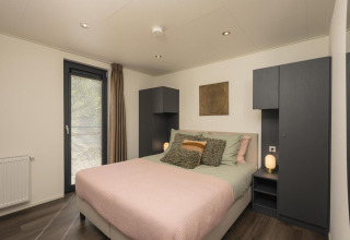 Dormitorio moderno en la cabaña Cannenburch con cama cómoda en Veluwepark de Bosgraaf, Países Bajos.