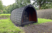 Una cabaña con techo de tejas en el césped de Het Amsterdamse Bos, Países Bajos, rodeada de árboles.