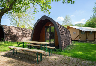 Pod presso Het Amsterdamse Bos nei Paesi Bassi con panchine di legno sull’erba e tenda sullo sfondo.
