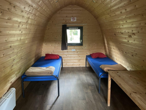 Interior de una cabaña de madera con dos camas individuales y ventana en Het Amsterdamse Bos, Países Bajos.