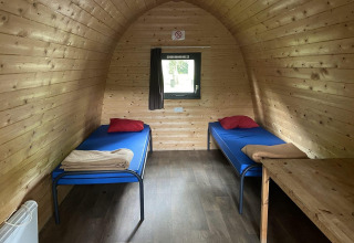 Interno di un pod in legno con due letti singoli, biancheria e finestra all'Het Amsterdamse Bos nei Paesi Bassi.