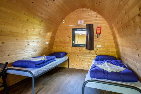 Dos camas individuales con ropa de cama azul en un pod de madera en Het Amsterdamse Bos, Países Bajos.