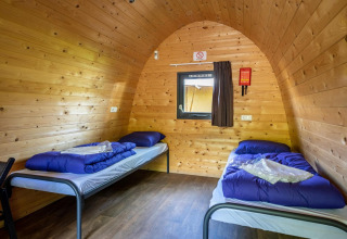 Deux lits simples avec draps bleus dans une pod en bois au Het Amsterdamse Bos, Pays-Bas, ambiance cosy.