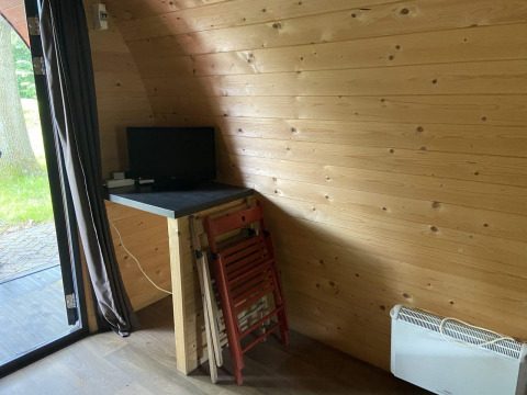 Pequeño escritorio con monitor y sillas plegables en una cabaña de madera en Het Amsterdamse Bos, Países Bajos.