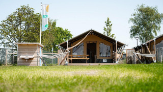 Tienda safari Villatent Compact con baño privado, hamaca y banco de picnic en entorno verde.