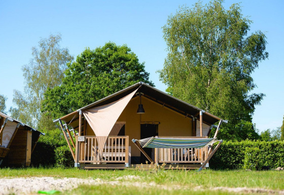Tienda safari Villatent Outback con porche y hamaca en Camping de Schatberg, Países Bajos, día soleado.