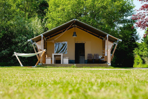 Tienda safari Villatent Nomad en Vakantiepark de Twee Bruggen, Países Bajos, rodeada de árboles y césped.