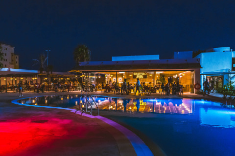 Imagen nocturna de Camping Costa del Sol Glamping Village con piscina iluminada y restaurante en Andalucía, España.