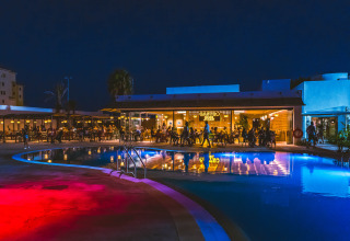 Avondbeeld van Camping Costa del Sol Glamping Village met verlicht zwembad en restaurant in Andalusië, Spanje.