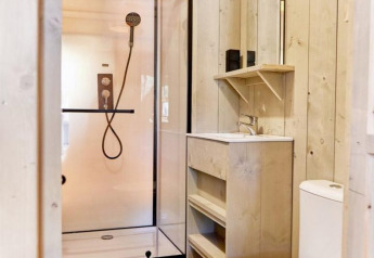 Modern bathroom in a safari tent at Camping Village Baia Blu La Tortuga, Italy, with shower, toilet and sink.