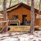 Tienda safari Villatent Outback entre pinos, con terraza de madera, hamaca y acogedor ambiente exterior.