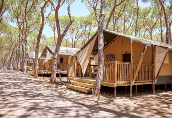 Safari tents of Villatent Outback at Camping Village Baia Blu La Tortuga, surrounded by pine trees in Italy.