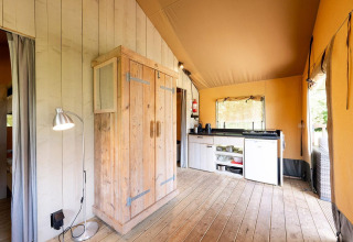 Binnenzicht van safaritent Villatent Wood op Camping Nautic Almata in Spanje, met keuken en houten vloer.