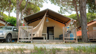 Tenda safari Villatent Outback con veranda, auto parcheggiata e pini, ideale per vacanze nella natura.