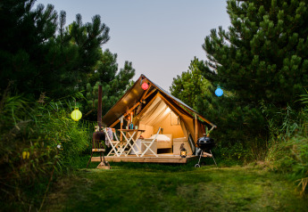Tente safari Lodge Mokki - UFO au Netl Camping Kallumaan aux Pays-Bas, entourée de pins au crépuscule.