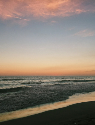 Atardecer en la costa cerca de Fuengirola, Andalucía, España, con suaves olas y cielo colorido.