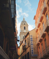 Calle pintoresca de Andalucía, España, con antiguos edificios de colores y una torre de iglesia al fondo.