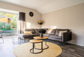 Modern living room at Velthorst lodge in De Wije Werelt, Netherlands, with corner sofa and large window.