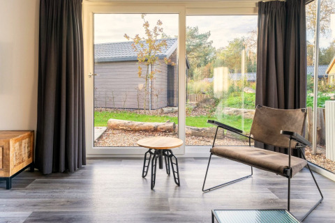 Salon lumineux au lodge Velthorst à De Wije Werelt, Pays-Bas, avec fauteuil moderne et vue sur le jardin.