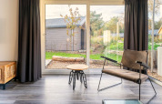 Salon lumineux au lodge Velthorst à De Wije Werelt, Pays-Bas, avec fauteuil moderne et vue sur le jardin.