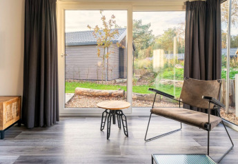 Lichte woonkamer in Velthorst lodge bij De Wije Werelt met moderne stoel en uitzicht op de tuin.