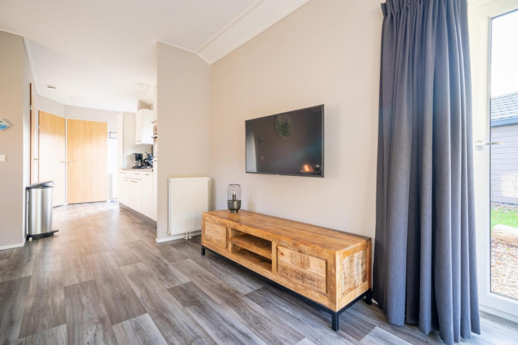 Acogedora y moderna cabaña en Velthorst de De Wije Werelt, Países Bajos, sala con televisor y muebles de madera.