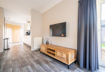 Acogedora y moderna cabaña en Velthorst de De Wije Werelt, Países Bajos, sala con televisor y muebles de madera.