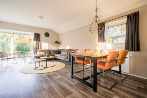 Luminoso salón-comedor en la cabaña Velthorst de De Wije Werelt, Países Bajos, con mobiliario moderno.