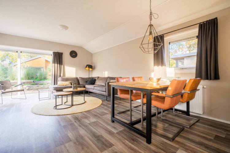 Luminoso salón-comedor en la cabaña Velthorst de De Wije Werelt, Países Bajos, con mobiliario moderno.