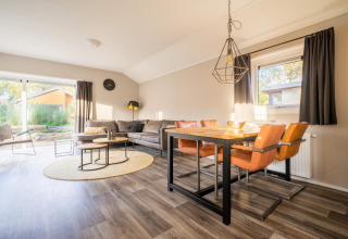 Luminoso salón-comedor en la cabaña Velthorst de De Wije Werelt, Países Bajos, con mobiliario moderno.