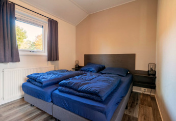 Slaapkamer met twee eenpersoonsbedden en blauw beddengoed in Velthorst Lodge, De Wije Werelt, Nederland.