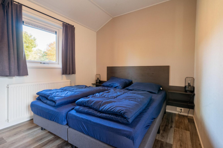 Dormitorio con dos camas individuales y ropa de cama azul en Velthorst Lodge, De Wije Werelt, Países Bajos.